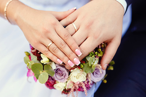 تصویری از دست یک عروس و داماد در دست هم به همراه حلقه ازدواج